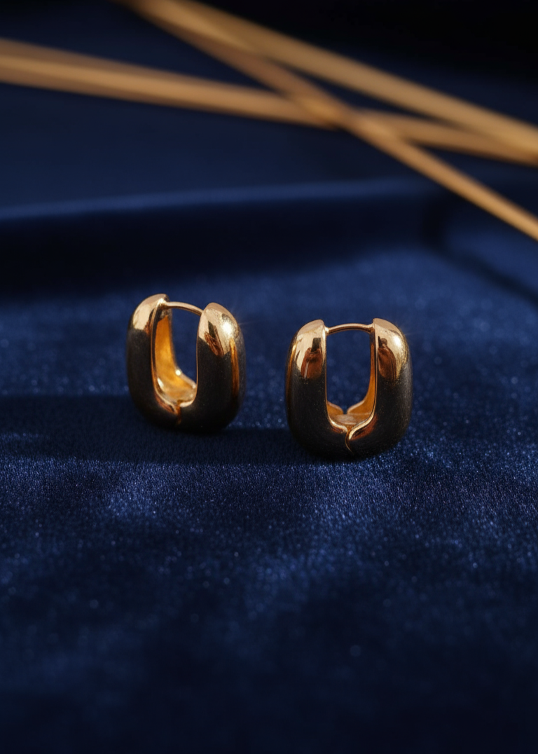 Gold hoop earrings on a dark blue fabric background