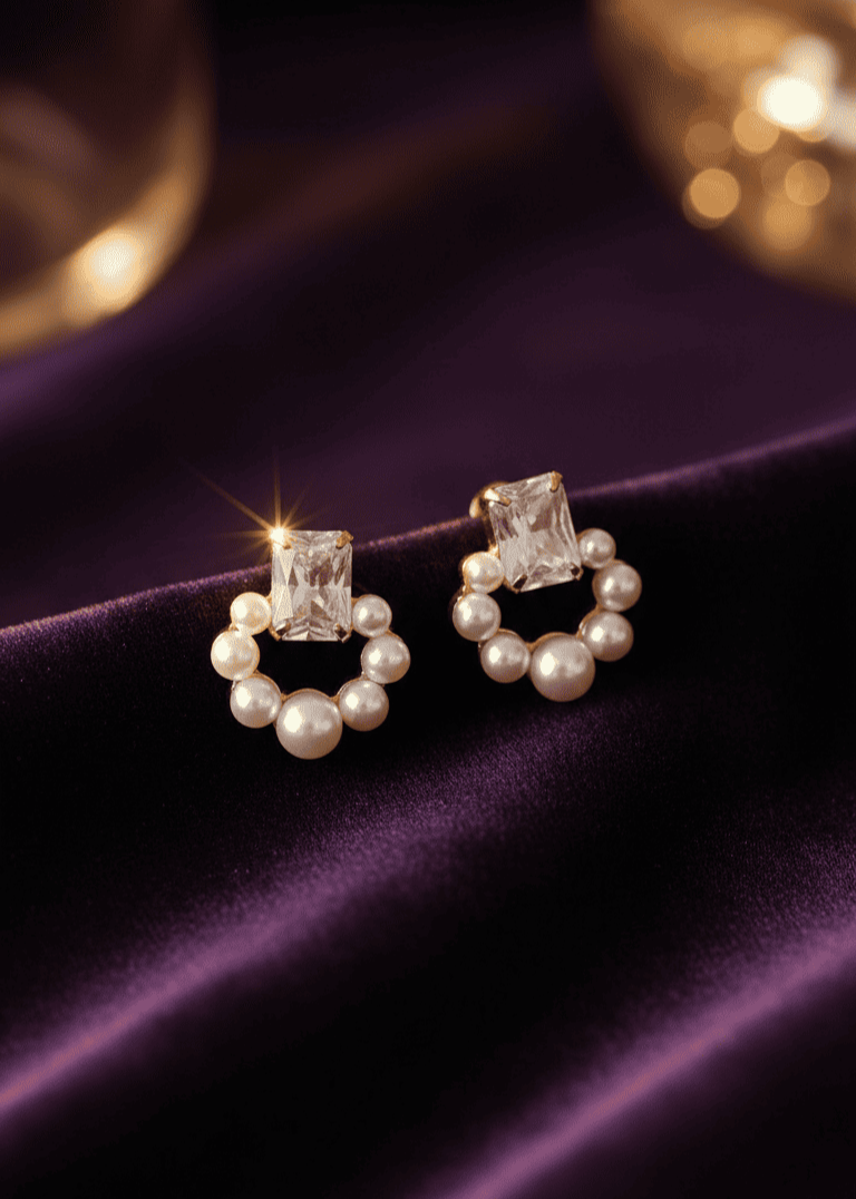 Pair of earrings with pearls and gemstones on a purple fabric background