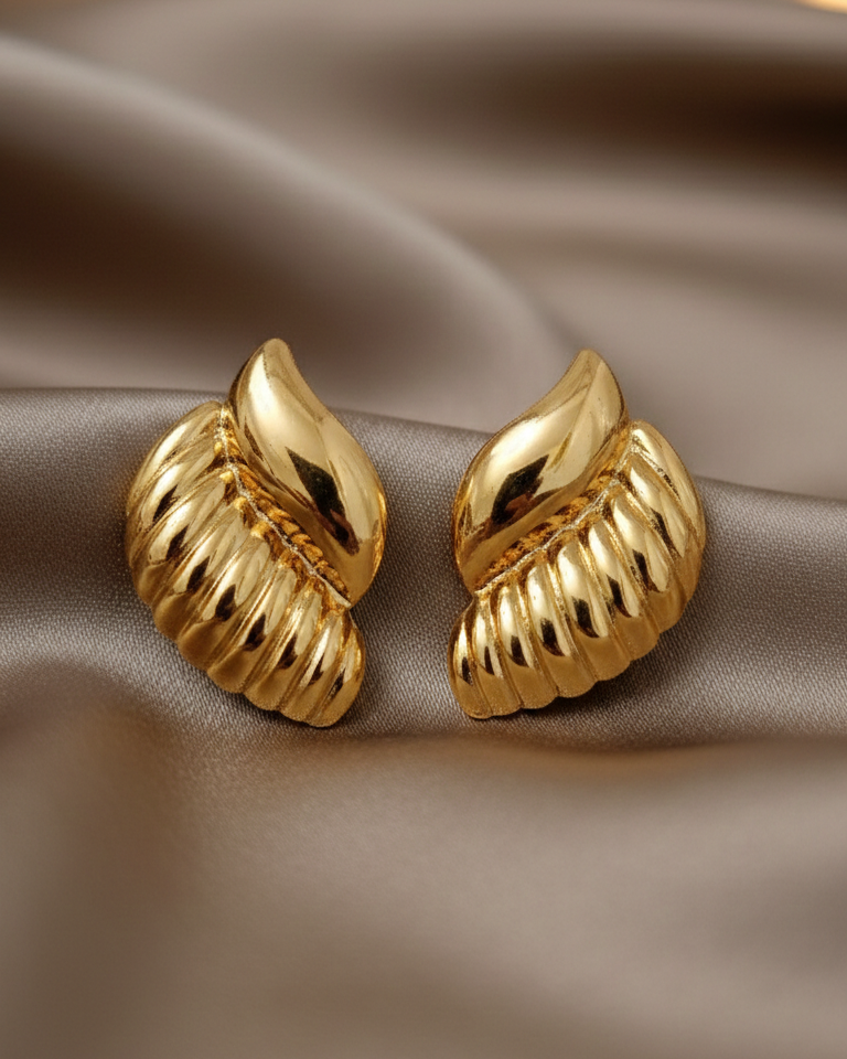Gold earrings on a brown fabric background
