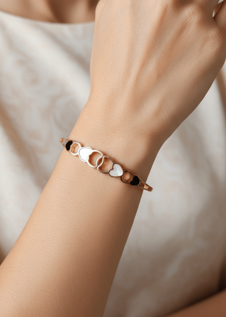 Bracelet with heart-shaped charms on a wrist against a neutral background