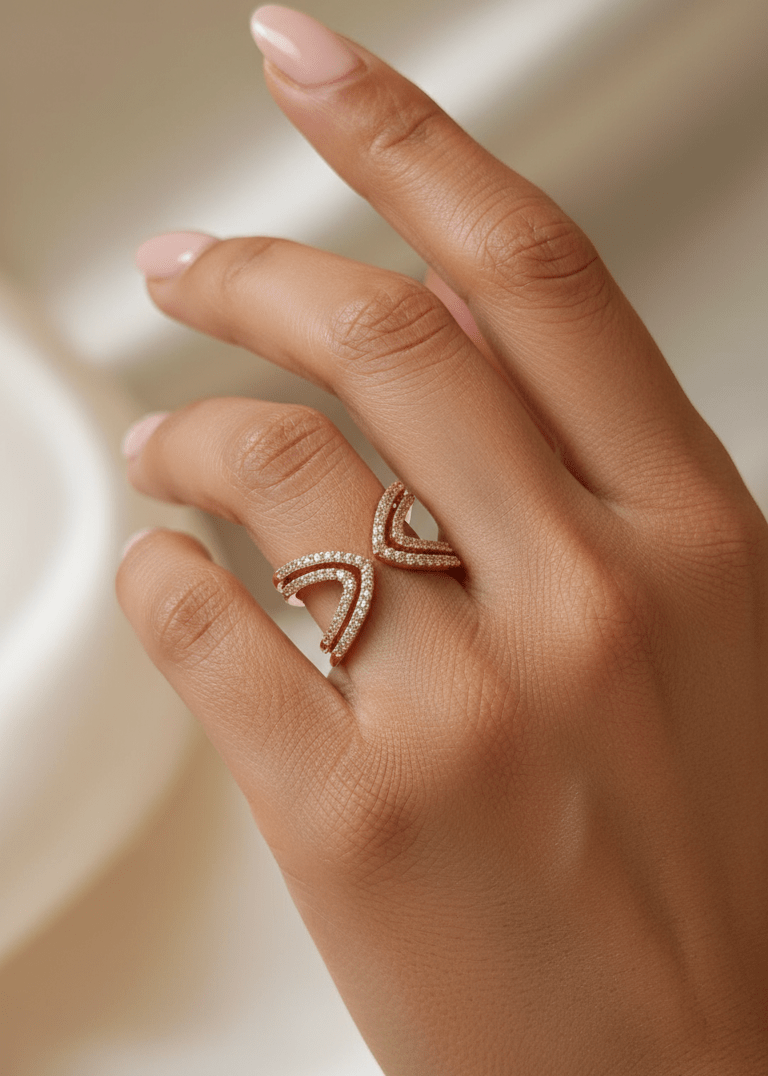 Hand wearing a rose gold ring with a design on a neutral background