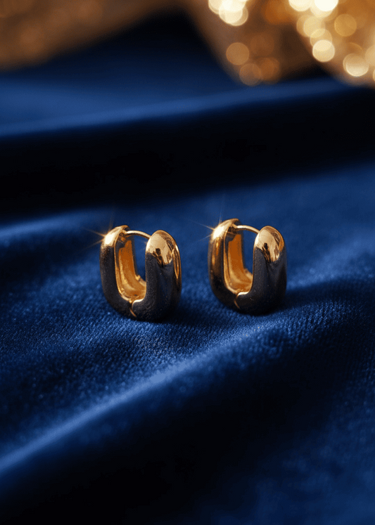 Gold hoop earrings on a blue fabric background with blurred golden lights.