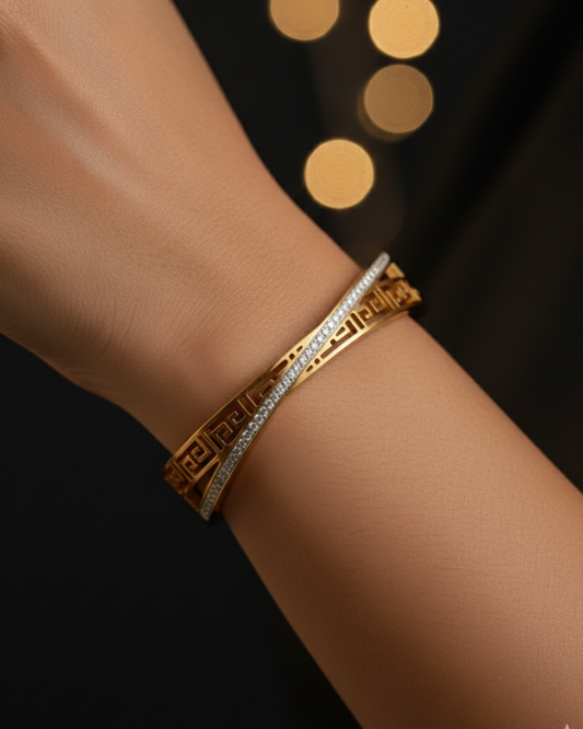 Gold bracelet with diamond accents on a wrist against a dark background