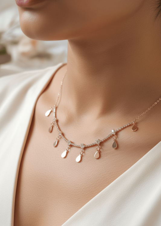 Necklace with teardrop-shaped pendants on a person wearing a white top.