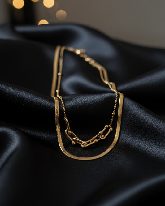 Gold necklace on black satin fabric with blurred lights in the background