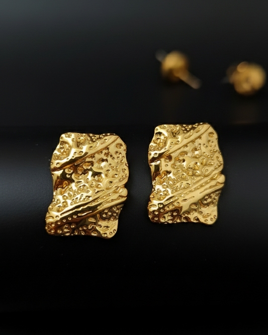 Gold textured earrings on a black background