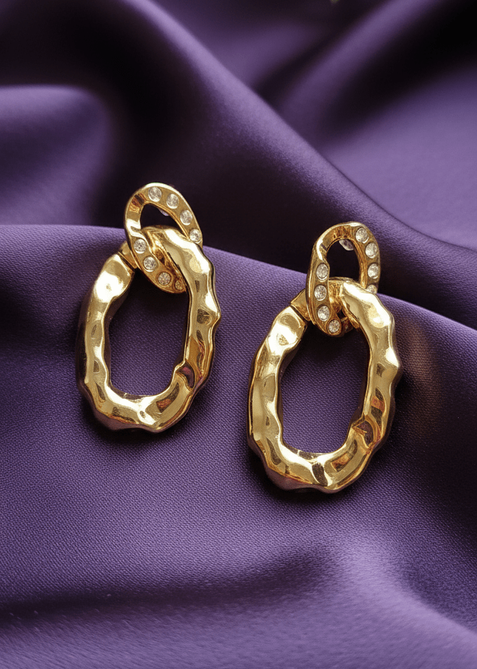 Gold hoop earrings on a purple fabric background