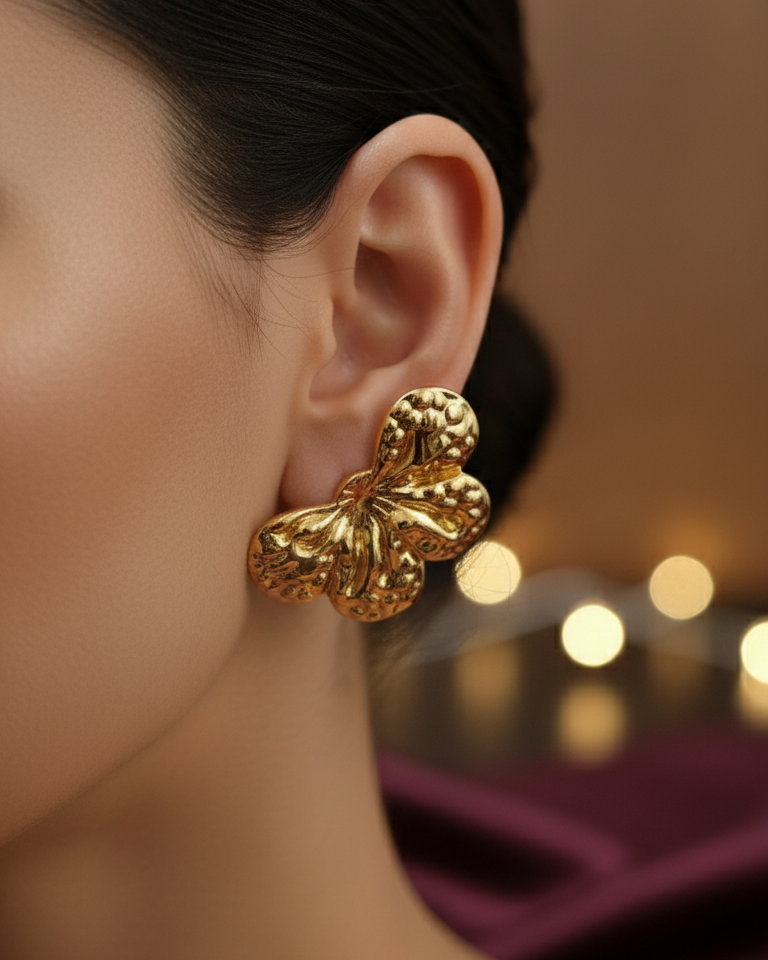 Gold Flower earrings worn by a model with a blurred background