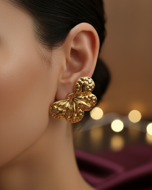 Gold Flower earrings worn by a model with a blurred background