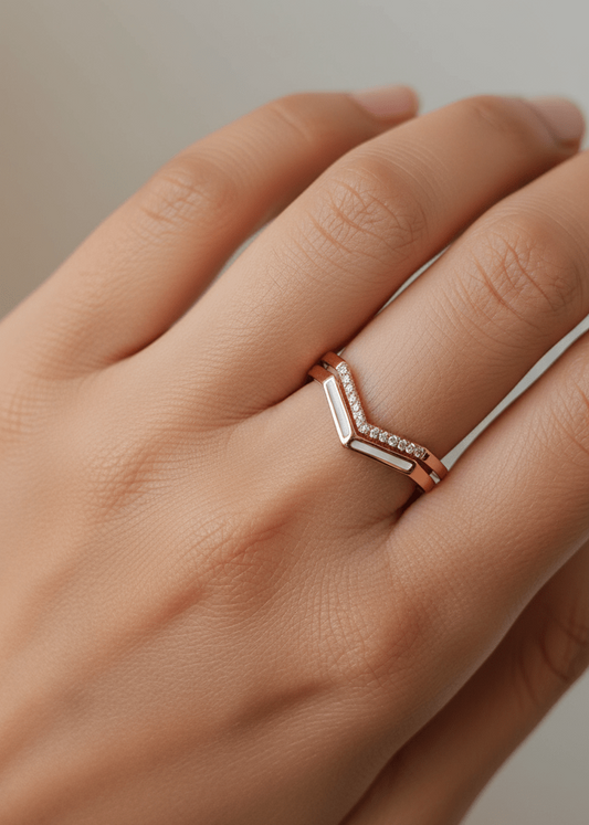 Rose gold ring with geometric design on a hand against a neutral background