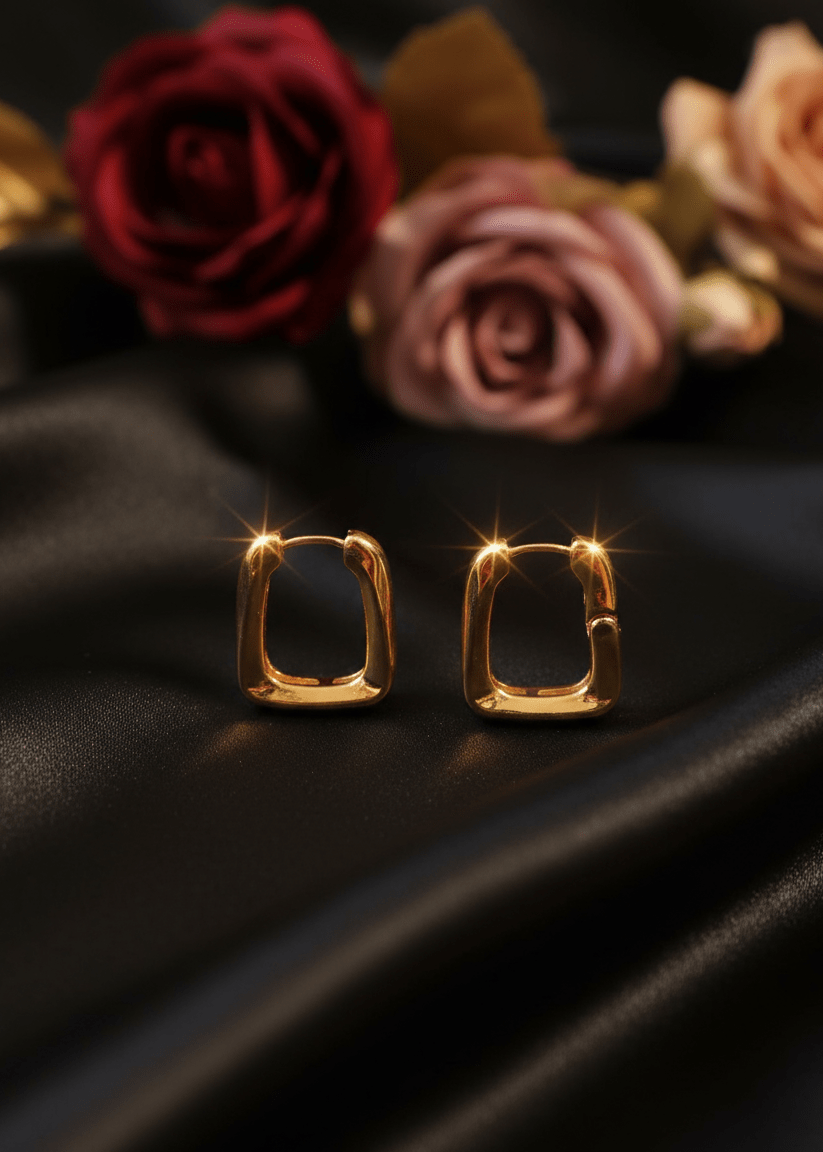 Gold hoop earrings on a dark fabric background with roses.