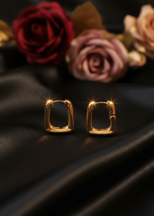 Gold hoop earrings on a dark fabric background with roses.