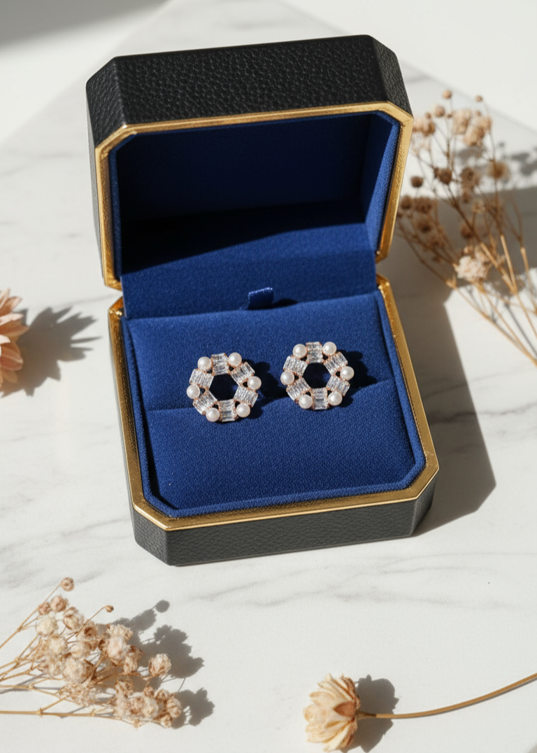 Pair of earrings in a jewelry box on a light surface with dried flowers.