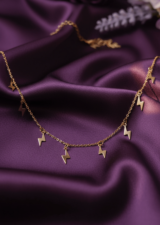 Gold necklace with star-shaped pendants on a purple fabric background