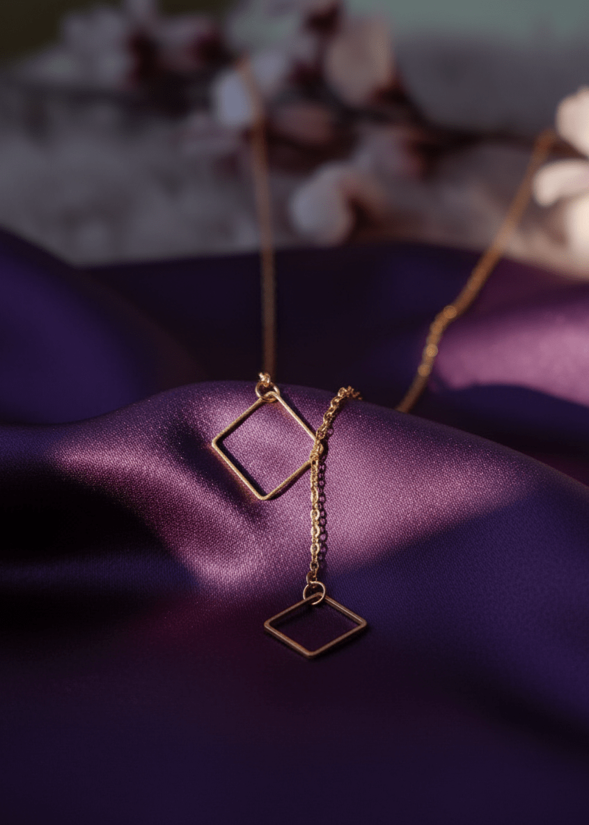 Gold necklace with square pendants on a purple fabric background