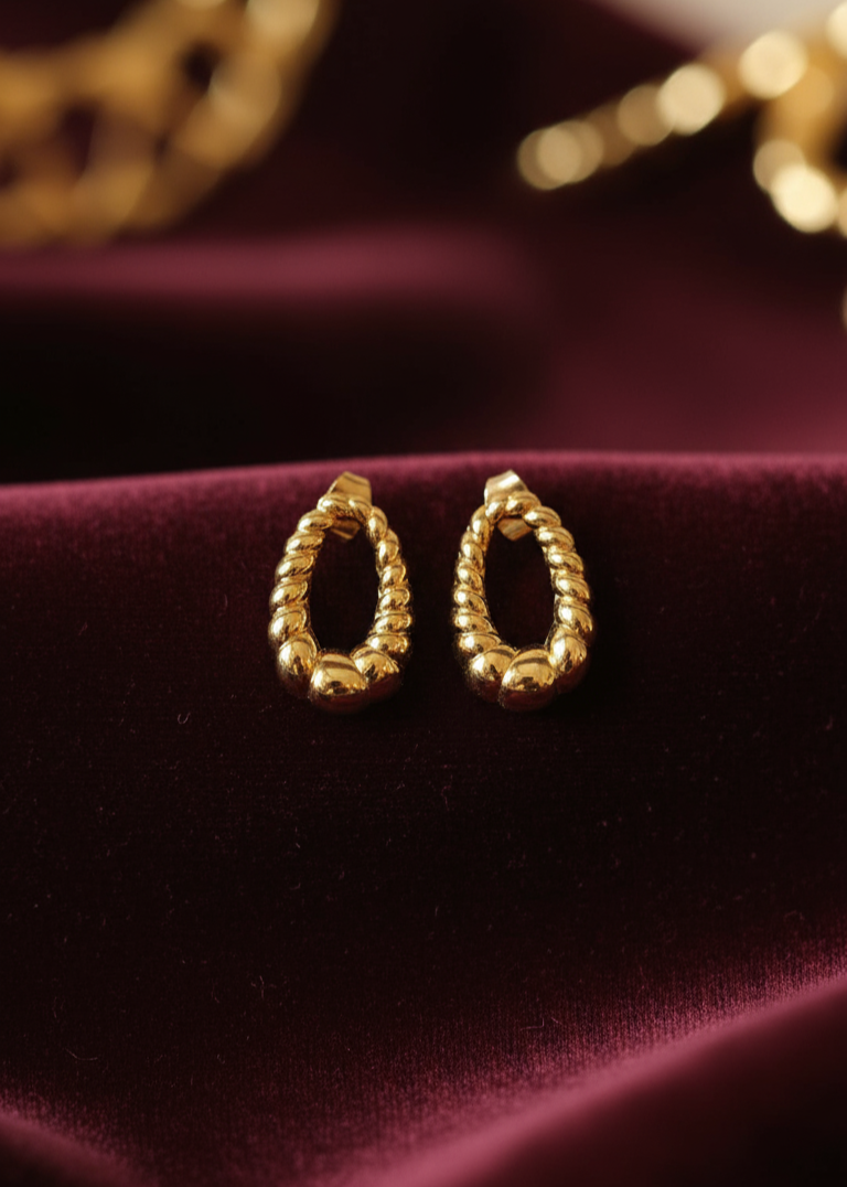 Gold hoop earrings on a burgundy fabric background
