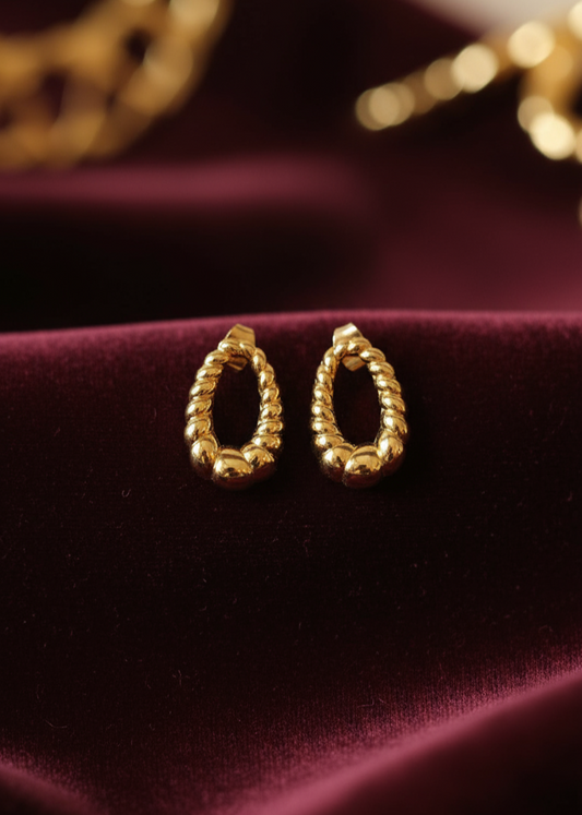 Gold hoop earrings on a burgundy fabric background
