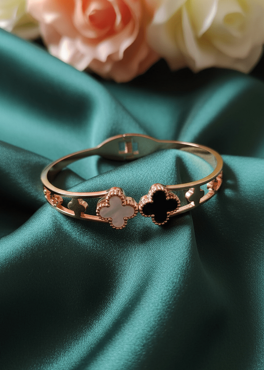 Rose gold bracelet with clover designs on a green satin background