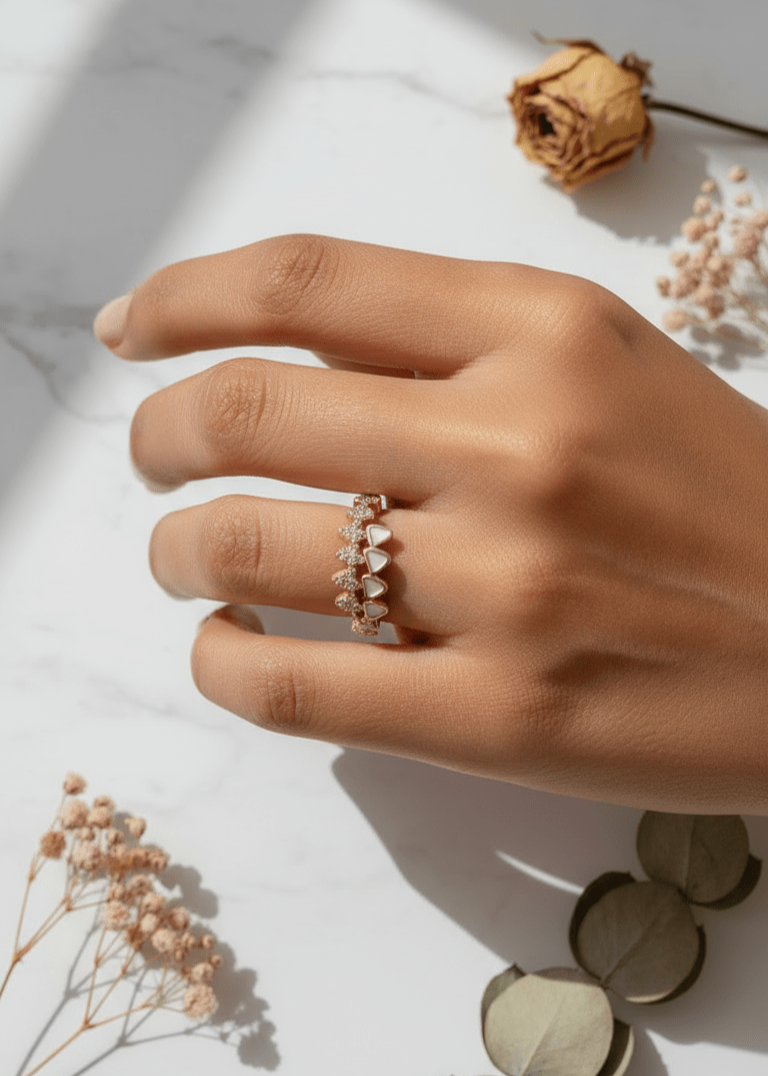 Hand wearing a delicate ring with dried flowers on a light background