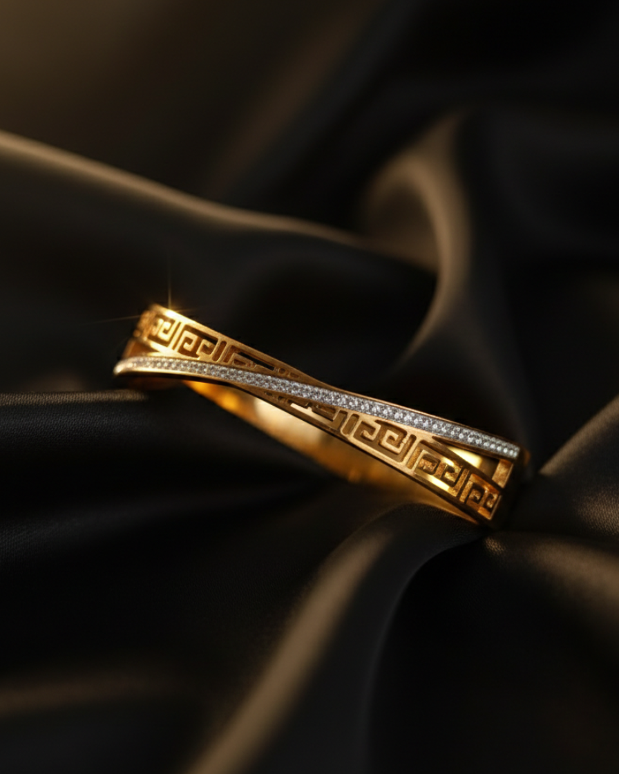 Gold ring with intricate design on a black satin background