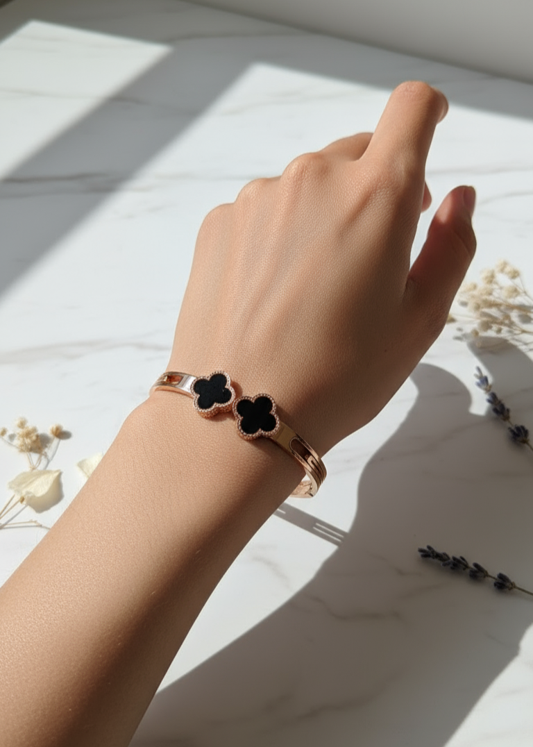 Hand wearing a bracelet with black flower charms on a light surface
